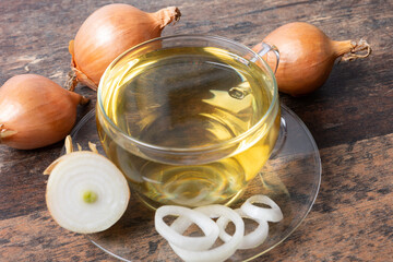 Heathy Onion tea on wooden table background with onions and slices around, transparent cup