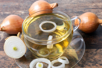 Wellness tea made of onions in transparent tea cup on wooden table background