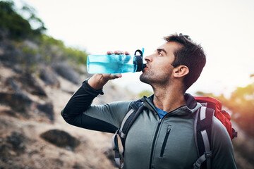 Hiking, fitness and man drinking water in nature with backpack for workout, training and adventure....