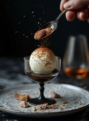 Closeup shot of a hand sprinkling toppings over a gourmet dessert with a black ornate spoon in an elegant setting