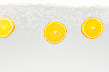 Textured photo. Slices of citrus, sweet and sour orange float in clear water with ice cubes against white background. Abstract wallpaper. Concept of food and drinks, summer,vitamins, nutrition.