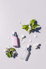 Two chic bottles with a cosmetic product for the care of young skin on a light background with...