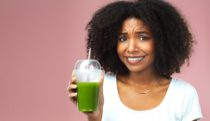 Disgust, nutrition and woman with green juice for detox, health or wellness weight loss diet. Gross, unhappy and female person drinking organic smoothie for vitamins isolated by studio background.