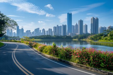 An urban pathway with lush greenery and vibrant flowers runs alongside a calm lake, leading towards towering skyscrapers