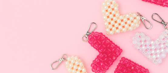 Banner with beaded keychains in a heart shape on a pink background.