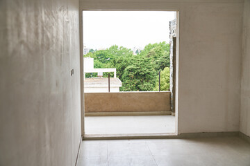 Interior of incomplete house room with balcony entrance at construction site