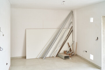 Wooden material leaning on white wall inside incomplete room at construction site