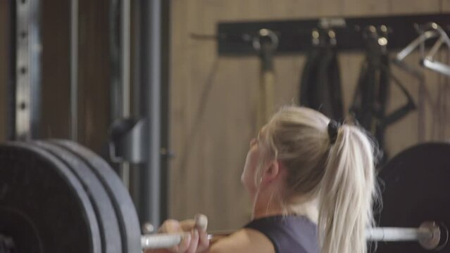 Strong athletic female in gym does impressive clean and jerk weightlifting move