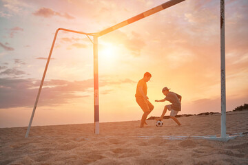 Father and Son playing football, family fun outdoors players on beach