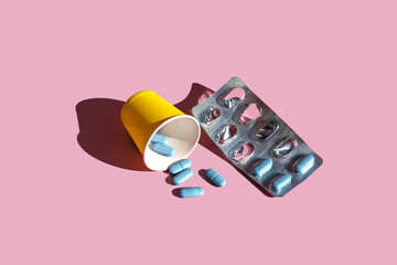 Blue pills with blister pack over pink background