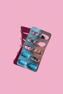 Blue tablets in blister pack over pink background