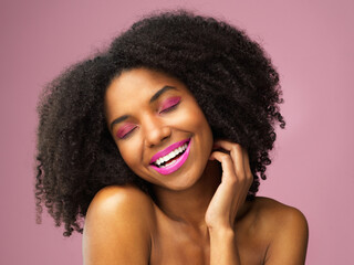 Black woman, beauty and smile with makeup in studio with cosmetics for skin isolated on pink...