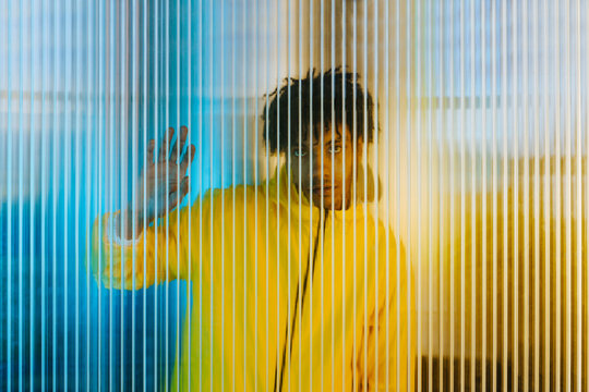 Young man standing behind striped wall