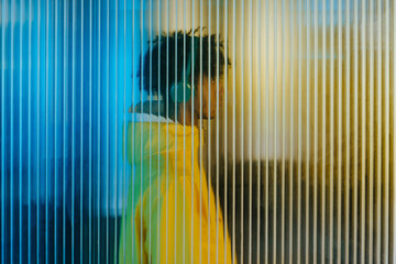 Young man in wireless headphones behind futuristic wall