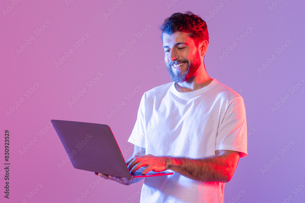 Aufkleber A man in a white shirt is seated, working on a laptop computer. He is focused on the screen, typing and scrolling. The background is a simple indoor setting with minimal distractions.