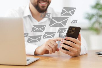 Smiling man with smartphone chatting at table indoors, closeup. Many illustrations of envelope as...