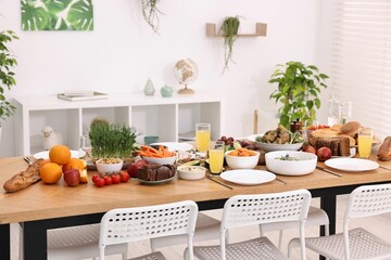 Healthy vegetarian food, glasses of juice, cutlery and plates on wooden table indoors