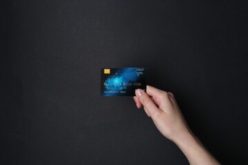 Woman holding credit card on black background, closeup