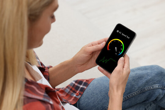 5G speed test. Woman using mobile phone at home, closeup