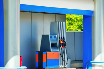 Car at a blue and orange themed fuel station with an automatic pump