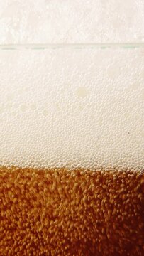 Close-up of beer glass with lager foamy beer pouring. Bubbles going upwards. Degustation. Concept of beer drink, brewery, taste, bar, degustation, festival, drink texture. Vertical layout