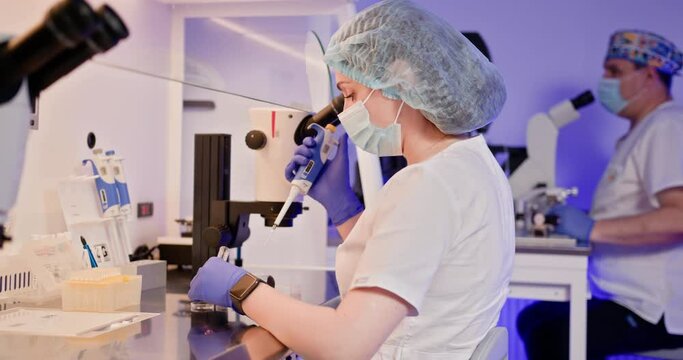 Embryologist in a laboratory carefully performing artificial fertilization of a human egg using specialized equipment. Displays a high-tech lab environment focused on reproductive science and IVF.