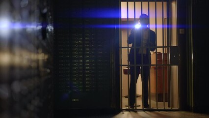 A security officer is examining a vault with a flashlight at a bank for safety inspection