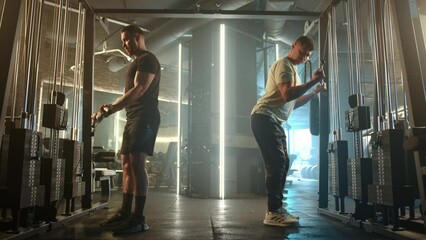 In a modern gym, two men are dedicated to strength training, fitness routines, and physical health as they exercise with cable machines. Their commitment and motivation are evident in their workout