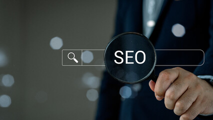 Businessman using magnifying glass focus to SEO icon to analyze SEO search engine optimization for...
