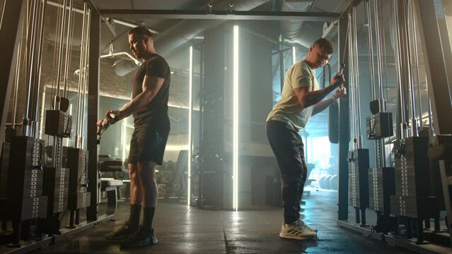 In a modern gym, two men are dedicated to strength training, fitness routines, and physical health as they exercise with cable machines. Their commitment and motivation are evident in their workout