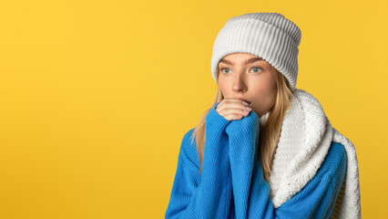 A young woman wearing a blue sweater and white beanie stands pensively against a bold yellow...