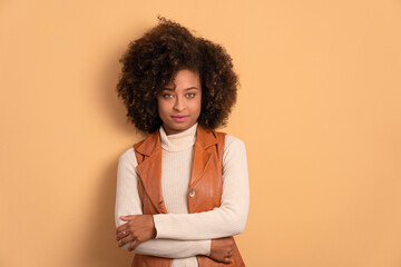 confident black young woman with arms crossed in beige colors. portrait, real people concept.