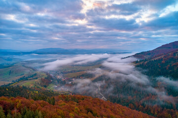 Fog spreads over the mountains at dawn. The sun rises on the horizon. Carpathians in the morning....