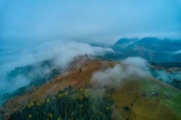 Fog spreads over the mountains at dawn. The sun rises on the horizon. Carpathians in the morning. Aerial drone view.