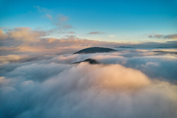 Flight over fog in Ukrainian Carpathians in summer. A thick layer of fog covers the mountains with...