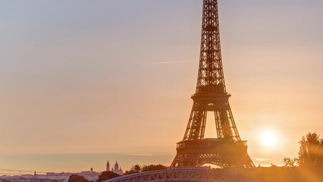 Eiffel Tower sunrise timelapse with boats on Seine river and in Paris, France. View from Grenelle bridge. Orange sky early morning