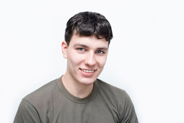 Active guy, college student, smiling happily on light background, boy is successfully graduating from college, dreams of successful career. Portrait of happy positive guy 19 years old smiling