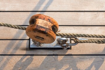 Wooden pulley with ropes on deck of sailing ship.
