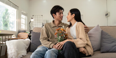 Young couple sitting together with flowers at home. Concept of love, affection, and intimacy