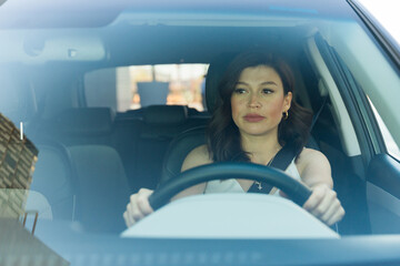 Concentrated adult woman skillfully steering her car, exemplifying safe and attentive automotive...