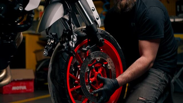 close up In a motorcycle repair shop mechanic removes the front wheel and rolls it back to replace the tires