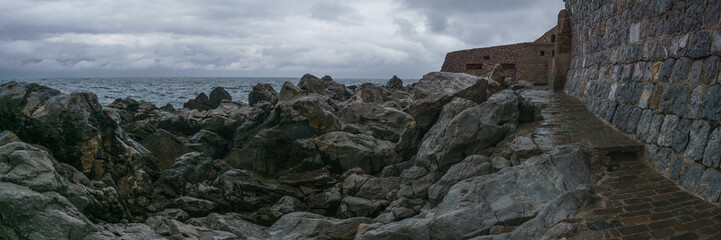 Panorama of medieval harbor wall at the mediterranean sea on a cloudy rainy day, Cefalu, Sicily, Italy