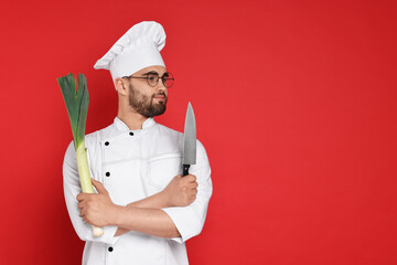 Professional chef with leek and knife having fun on red background. Space for text