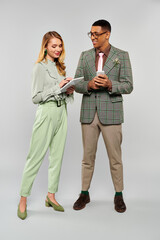 A captivating couple in vibrant green suits and pants stand lovingly together.