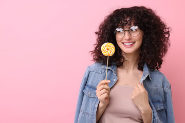 Beautiful woman with lollipop on pink background, space for text
