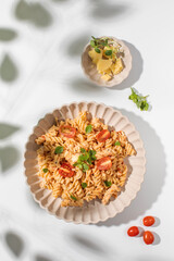 Plate of spiral pasta with feta cheese and cherry tomatoes, garnished with fresh herbs
