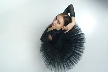 portrait of a young ballerina in a black tutu dancing with her hands moving top view, immersion in...