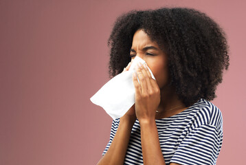 Tissue, blowing and nose with black woman in studio for sick or illness with allergies isolated on...