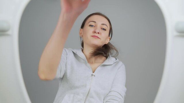 Woman gets up from toilet after defecating, straightens pants and throws inside used toilet paper. View from toilet bottom. Cleanliness and hygiene concept