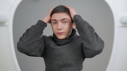 Boy teenager standing in front of toilet. He startled or frustrated by something in bowl, feeling bad smell. View from toilet bottom. Cleanliness and hygiene concept